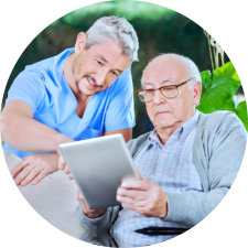 caregiver assisting the old man on how to use the tablet